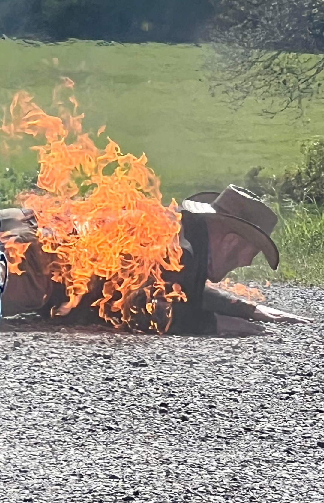 Ray Myers performing a full-body fire burn stunt in cowboy hat and duster