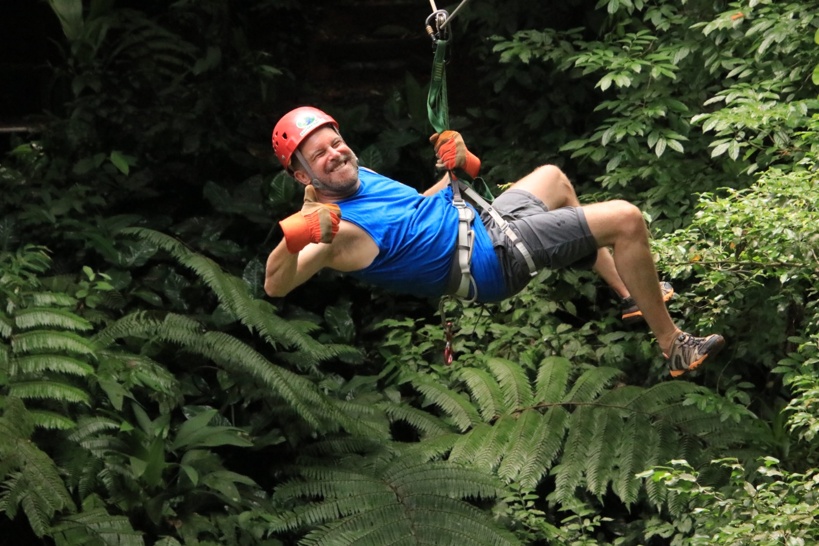 Ray Myers zip lining through Costa Rican rainforest, giving a thumbs up